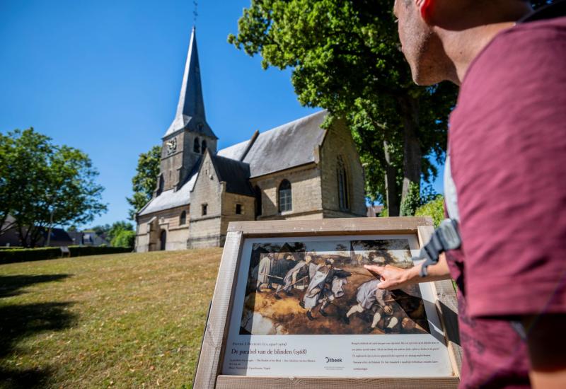 Bezoeker bekijkt in Sint-Anna Pede het infopaneel van de Sint-Anna kerk